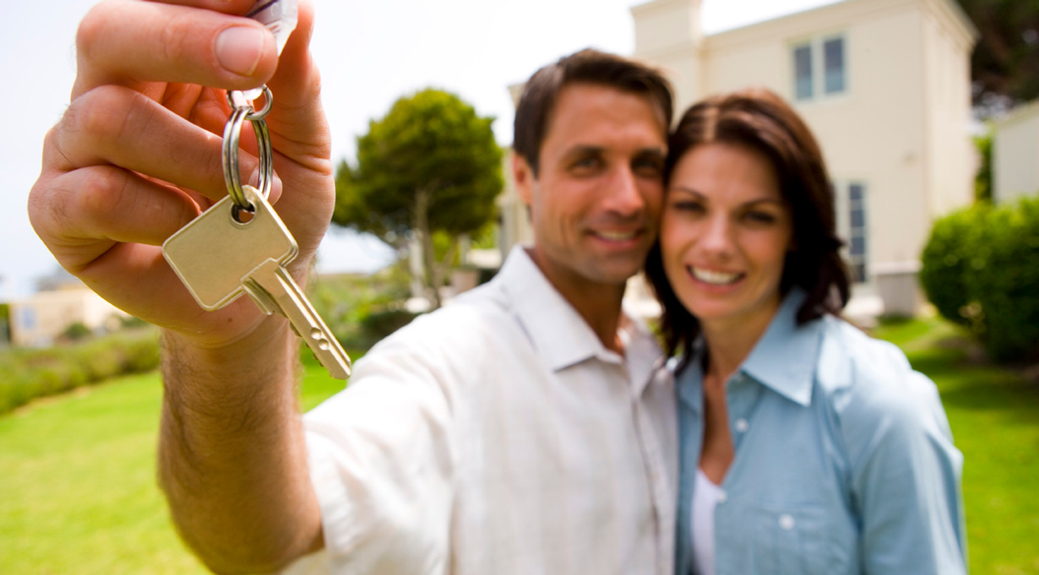 Couple holding keys in front of their new home